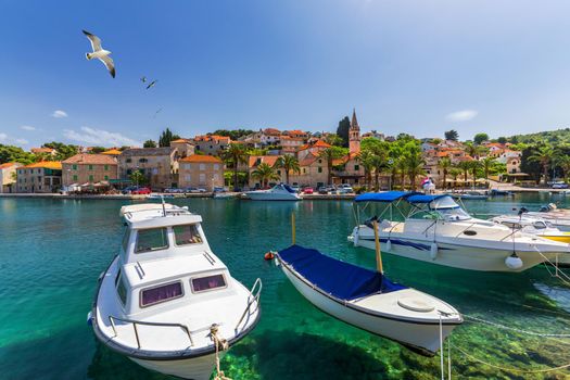 Splitska village with beautiful port and seagull's flying over the village, Brac island, Croatia. Fishing boats in Splitska village on Brac island seafront view, Dalmatia, Croatia, Croatia.
