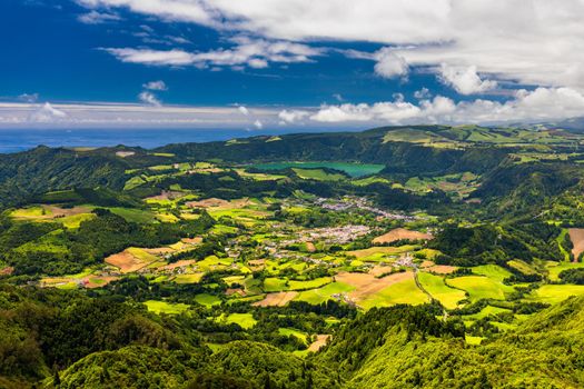 View of Furnas town and lake (Lagoa das Furnas) on Sao Miguel Island, Azores, Portugal from the Miradouro do Salto do Cavalo viewpoint. A tranquil scene of lush foliage and town in a volcanic crater