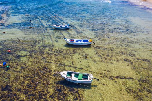 Vintage wooden boat in coral sea. Boat drone photo. Fishing boats in clear turquoise ocean, top view. Small fishing boat moored in blue clean transparent water. Aerial view. Peniche, Portugal.