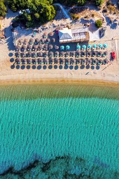 View from above, stunning aerial view of an amazing beach with beach umbrellas and turquoise clear water. Top view on sun loungers under umbrellas on the sandy beach. Concept of summer vacation. 