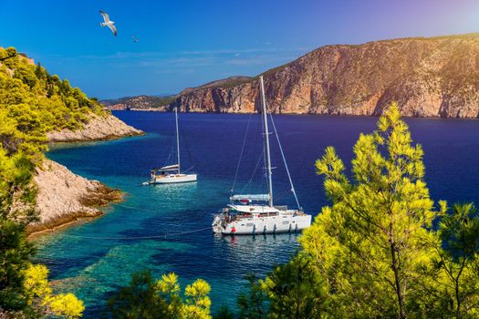 Aerial view of anchored sailing yacht in emerald sea. Aerial view of a boat. Outdoor water sports, yachting. Aerial view of anchoring yacht in open water. Ocean and sea travel and transportation