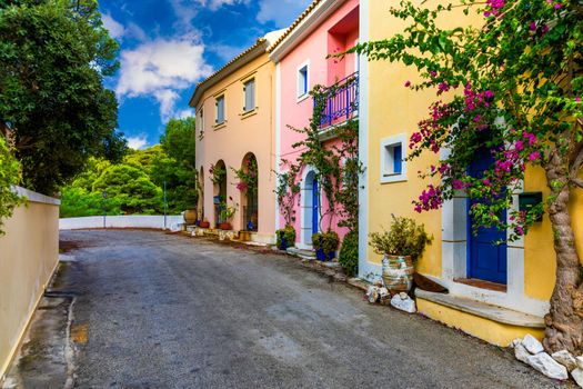 Traditional street with greek houses with flowers in Assos, Kefalonia island. Traditional colorful greek houses in Assos village. Blooming fuchsia plant flowers. Kefalonia island, Greece