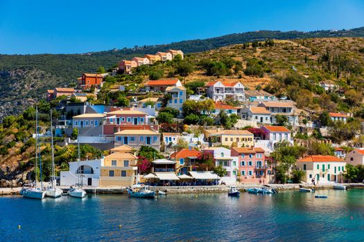 Turquoise colored bay in Mediterranean sea with beautiful colorful houses in Assos village in Kefalonia, Greece. Town of Assos with colorful houses on the mediterranean sea, Greece. 