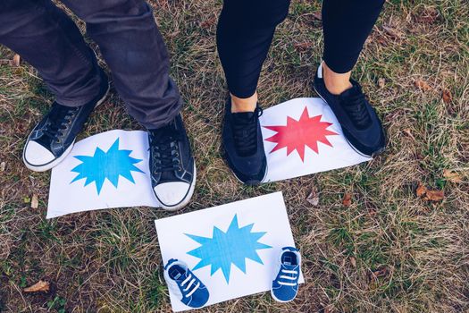 Young couple waiting for baby. Expecting parents with little baby boy shoes. Concept of Parents-To-Be. Shoes and sneakers of parents and expected baby. Mom, dad and the future baby Shoes.