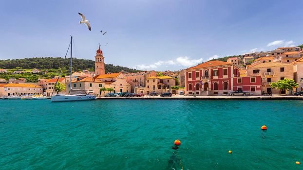 Panorama of picturesque town Pucisca in Croatia, Island Brac, Europe. Pucisca town mediterranean panorama with seagull's flying over the town. Croatia, Island Brac, Europe.