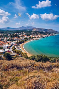 Greek holidays, beautiful Kalyves village with turquoise sea in Crete island, Greece. View of Kalyves beach, Crete. Seagulls flying over the beach in Kalyves, Crete, Greece