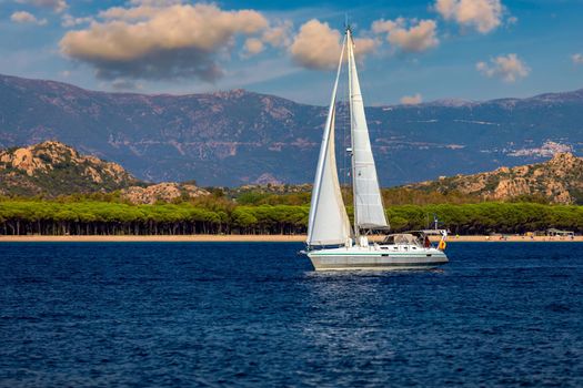 Yacht anchoring in crystal clear turquoise water in front of the tropical island, alternative lifestyle, living on a boat. Aerial view of yacht at anchor on turquoise water, showing luxury, wealth.