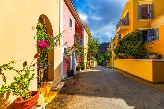 Traditional street with greek houses with flowers in Assos, Kefalonia island. Traditional colorful greek houses in Assos village. Blooming fuchsia plant flowers. Kefalonia island, Greece