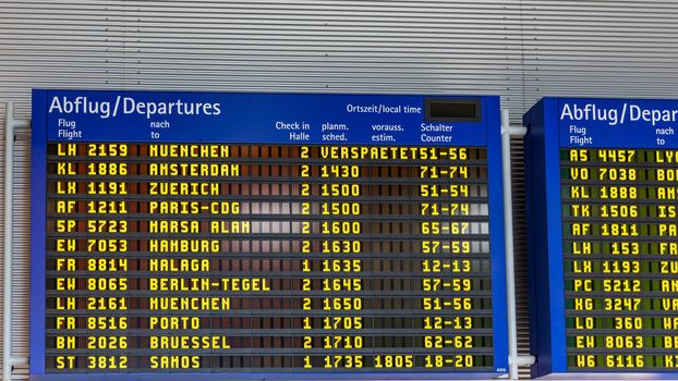 Airport flight information displayed on departure board, flight status changing. Flight schedule screen at airport showing different destinations. 