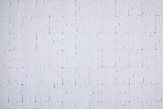 White jigsaw puzzle. White puzzle pieces on color background. Unfinished white jigsaw puzzle pieces on color background. 