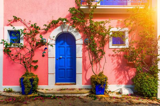 Traditional street with greek houses with flowers in Assos, Kefalonia island. Traditional colorful greek houses in Assos village. Blooming fuchsia plant flowers. Kefalonia island, Greece