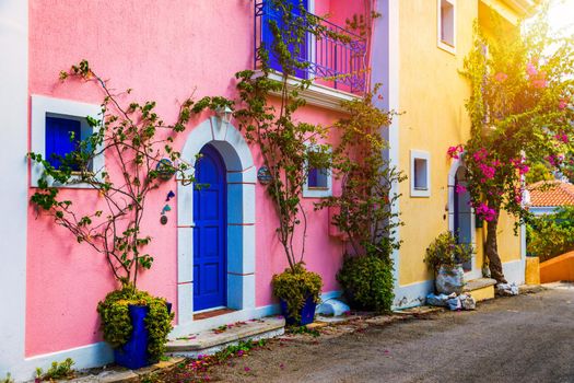Traditional street with greek houses with flowers in Assos, Kefalonia island. Traditional colorful greek houses in Assos village. Blooming fuchsia plant flowers. Kefalonia island, Greece