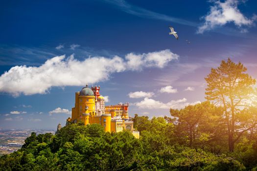 Famous historic Pena palace part of cultural site of Sintra against sunset sky in Portugal. Panoramic View Of Pena Palace, Sintra, Portugal. Pena National Palace at sunset, Sintra, Portugal. 