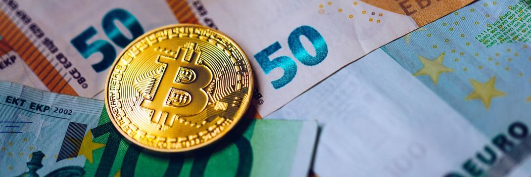 Golden bitcoin over Euro money. Bitcoin cryptocurrency. Crypto currency concept. Bitcoin with euro bills. Bitcoins stacked on euro banknotes.