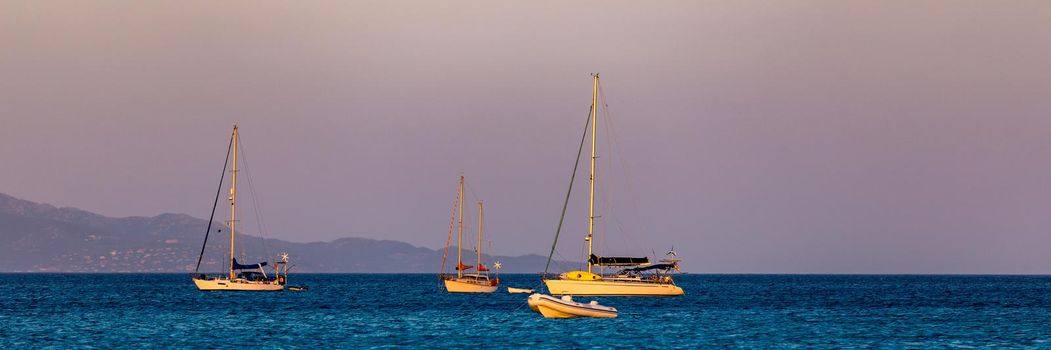 Aerial view of anchored sailing yacht in emerald sea. Aerial view of a boat. Outdoor water sports, yachting. Aerial view of anchoring yacht in open water. Ocean and sea travel and transportation