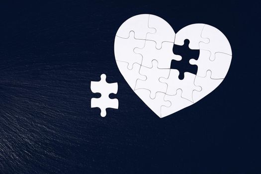 Heart-shaped jigsaw puzzle on color background. Puzzle heart on wooden background. A missing piece of the heart puzzle. Heart shape jigsaw puzzle. Puzzles in the shape of a heart. 