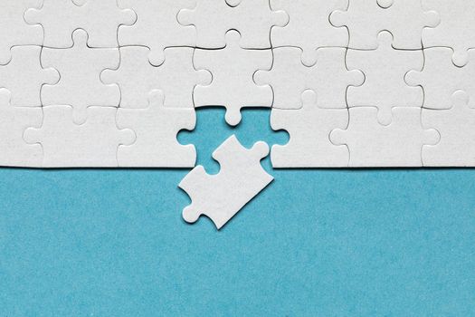 White jigsaw puzzle pieces. Fill in pieces of the jigsaw puzzle. Complete the jigsaw puzzle with the missing pieces. Fragment of a folded white jigsaw puzzle.