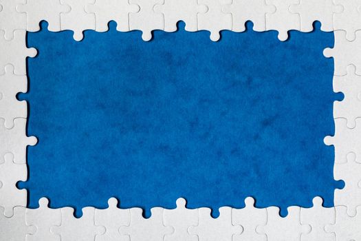 Framing in the form of a rectangle, made of a white jigsaw puzzle. Frame text and jigsaw puzzles. Frame made of jigsaw puzzle pieces on blue background.