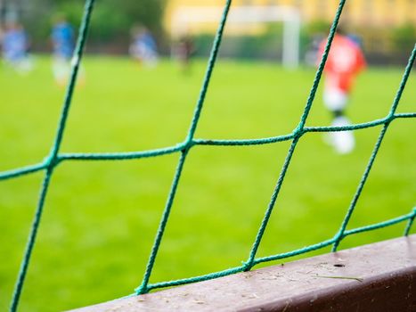 Soccer game behind the barrier or fence, the goal keeper in red wearing