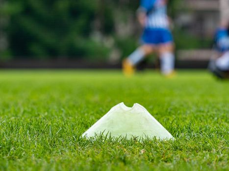 Sport plastic training marker on a grass training venue. Players running in a blurred background