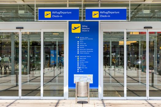 Airport terminal building gate entrance and automatic glass door with info text in german and english. Modern airport glass wall aisle window and door. Terminal entrance, automatic glass doors.
