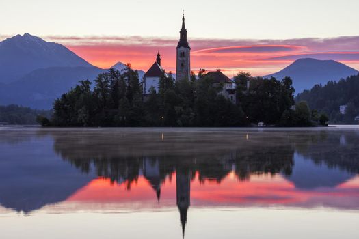 Dramatic sunrise on lake Bled, sunrise view on Bled lake, island, Pilgrimage Church of the Assumption of Maria and Castle with mountain range (Stol, Vrtaca, Begunjscica). Bled, Slovenia,
