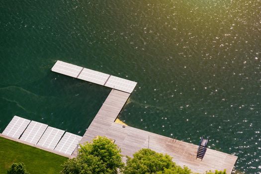 Empty wooden pier close to Bled lake, swimming area of the Bled lake under the sunny sky. Platform beside lake. Wooden pier on the lake. Bled, Slovenia
