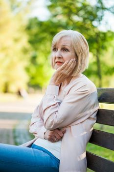 Lonely adult woman sitting in park in despair.