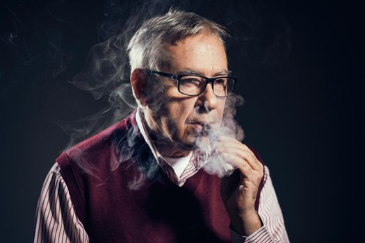 Portrait of senor man who is smoking electronic cigarette.