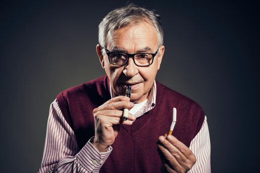Portrait of senior man who is decided to quit smoking cigarettes in favor of electronic cigarette.