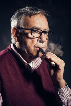 Portrait of senor man who is smoking electronic cigarette.