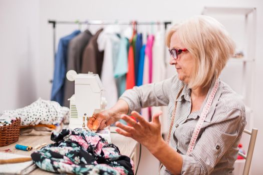 Adult woman is sewing in her studio. She is frustrated because she made a mistake.