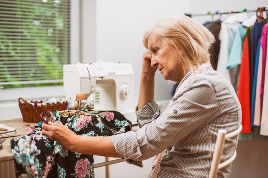 Adult woman is sewing in her studio. She is frustrated because she made a mistake.