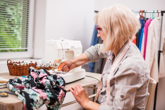 Adult woman is sewing in her studio.