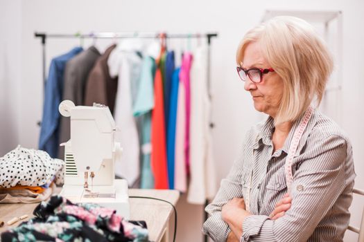 Adult woman is sewing in her studio. She is frustrated because she made a mistake.