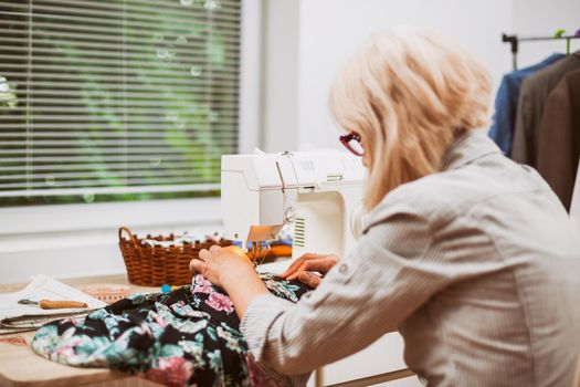 Adult woman is sewing in her studio.