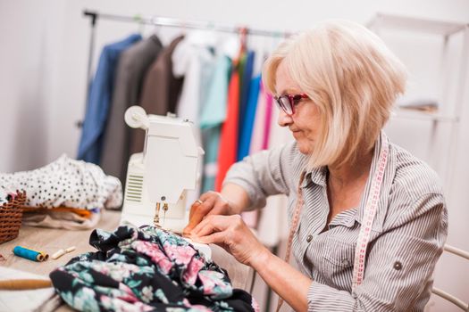 Adult woman is sewing in her studio. She is frustrated because she made a mistake.