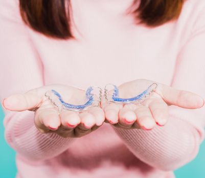 Close up hands of young woman holding silicone orthodontic retainers for teeth, Teeth retaining tools after removable braces, isolated blue background, Dental hygiene healthy care concept