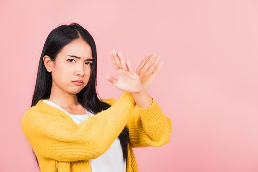 Portrait Asian beautiful young woman unhappy or confident standing wear holding two cross arms say no X sign, studio shot isolated pink background, Thai female pose reject gesture with copy space