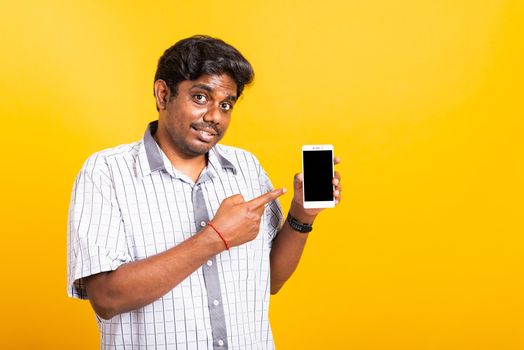 Asian happy portrait young black man smile standing wear shirt making finger pointing on smart digital mobile phone blank screen isolated, studio shot yellow background with copy space