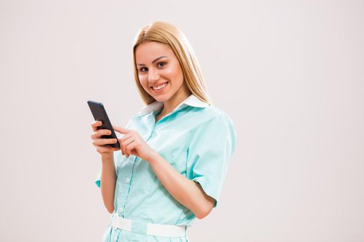 Portrait of young nurse who is using smartphone.