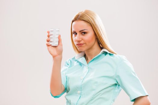 Portrait of young nurse who is holding pills.