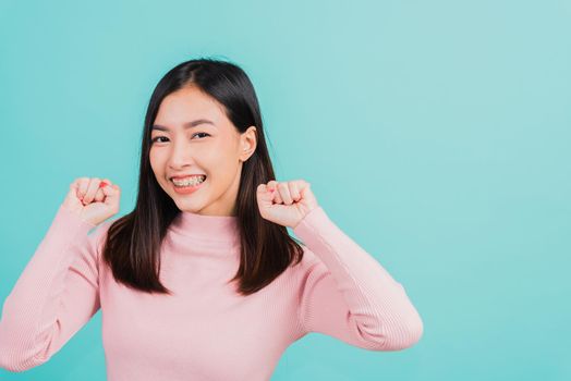 Happy young Asian beautiful woman smiling wear silicone orthodontic retainers on teeth surprised she is excited screaming and raise hand make gestures wow, studio shot isolated on blue background