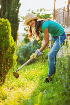 Young happy woman is hoeing the garden.