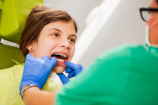 Dentist is examining teeth of a little girl.