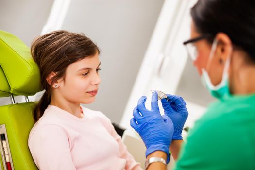 Dentist is teaching little girl about braces.