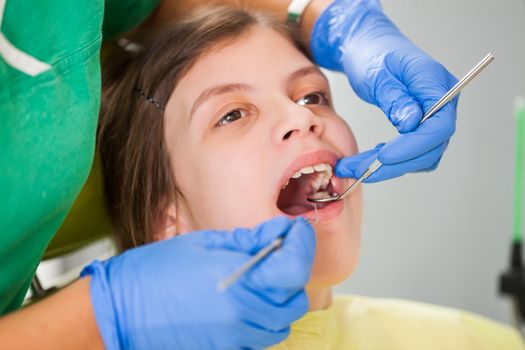 Dentist is examining teeth of a little girl.