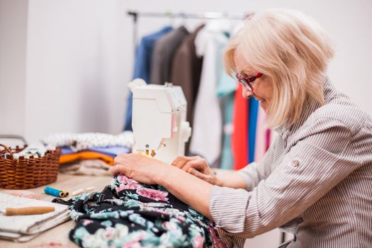 Adult woman is sewing in her studio.