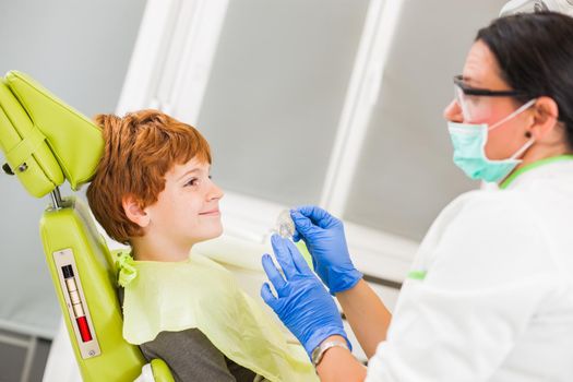 Dentist is teaching little boy about braces.
