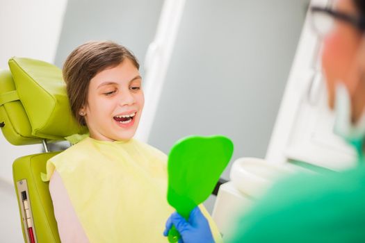 Little girl is looking at her teeth at dentist.